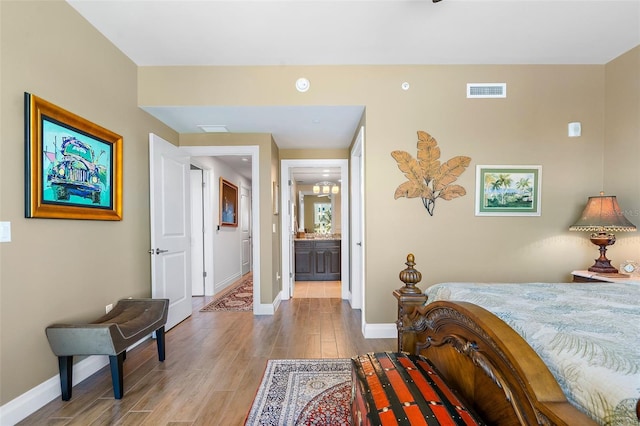 bedroom with hardwood / wood-style flooring and ensuite bathroom