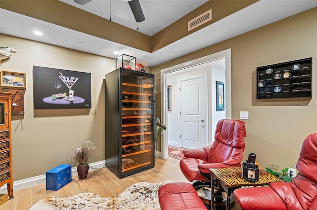 living area with ceiling fan, hardwood / wood-style floors, and beverage cooler