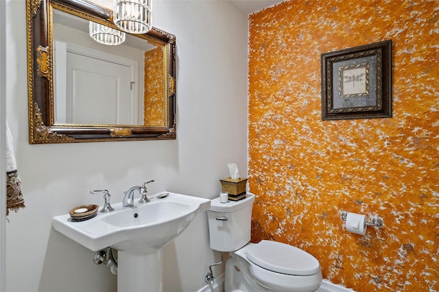 bathroom featuring toilet and a notable chandelier