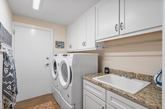 laundry area featuring cabinets, independent washer and dryer, sink, and hardwood / wood-style floors