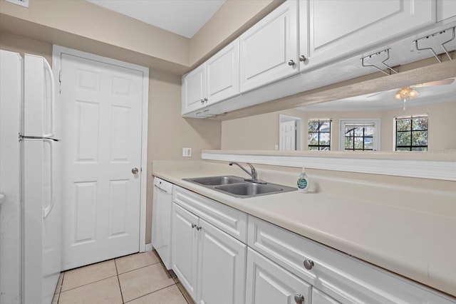 kitchen with light tile patterned floors, white appliances, a sink, white cabinets, and light countertops