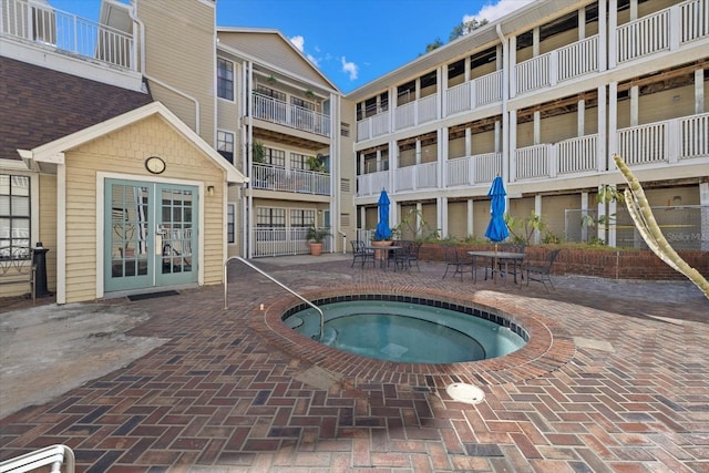 view of pool with french doors, a patio area, and a hot tub