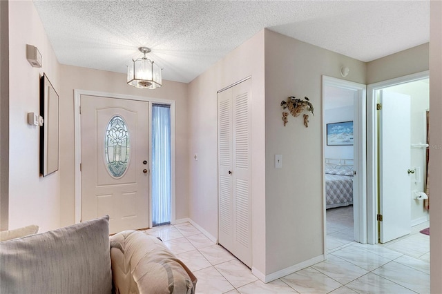 entryway with light tile patterned flooring and a textured ceiling