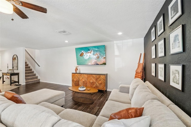 living room with a textured ceiling, dark hardwood / wood-style flooring, and ceiling fan