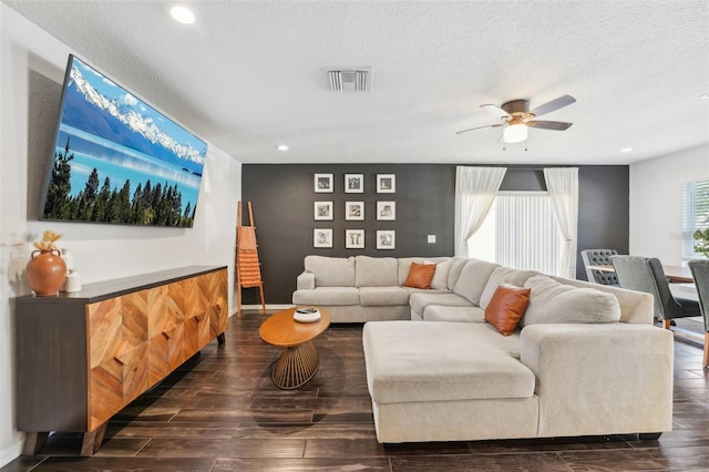 living room with ceiling fan, dark hardwood / wood-style flooring, and a textured ceiling