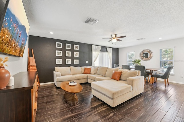 living room featuring a textured ceiling, dark hardwood / wood-style flooring, and ceiling fan