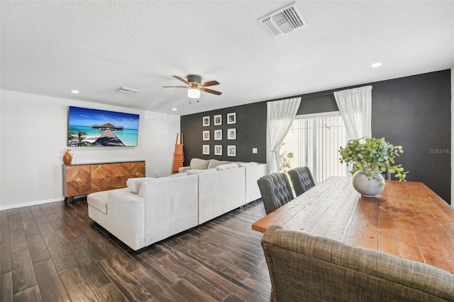 living room with a textured ceiling, ceiling fan, and dark hardwood / wood-style floors