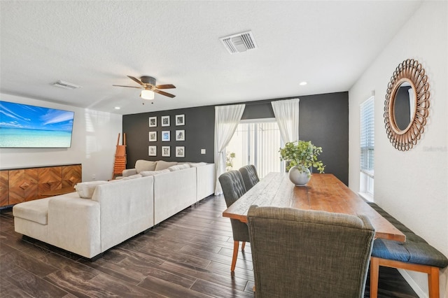 dining space with ceiling fan, dark wood-type flooring, and a textured ceiling