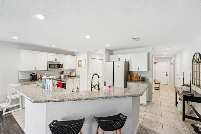 kitchen featuring appliances with stainless steel finishes, white cabinetry, and a large island with sink