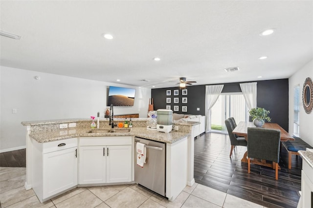 kitchen with sink, light stone counters, light hardwood / wood-style flooring, stainless steel dishwasher, and white cabinets