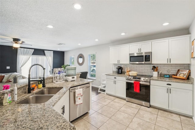 kitchen with stainless steel appliances, white cabinetry, ceiling fan, and sink