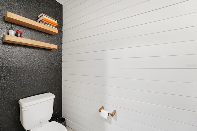 bathroom with toilet and wooden walls