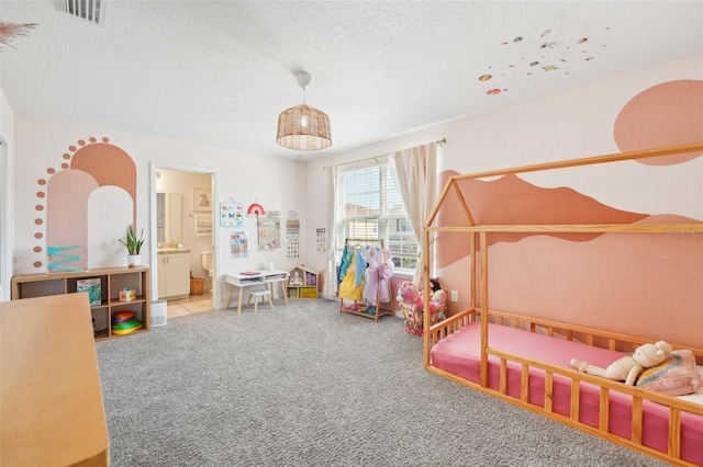 bedroom featuring light carpet, a textured ceiling, and ensuite bath