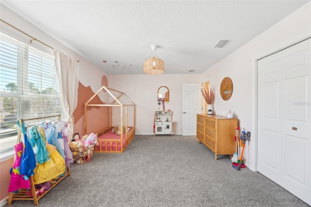 rec room with carpet floors, a textured ceiling, and a wealth of natural light