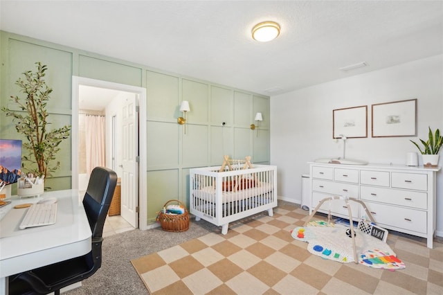 carpeted bedroom featuring a textured ceiling and a nursery area