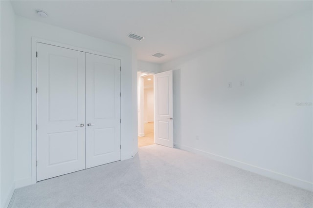 unfurnished bedroom featuring light carpet and a closet