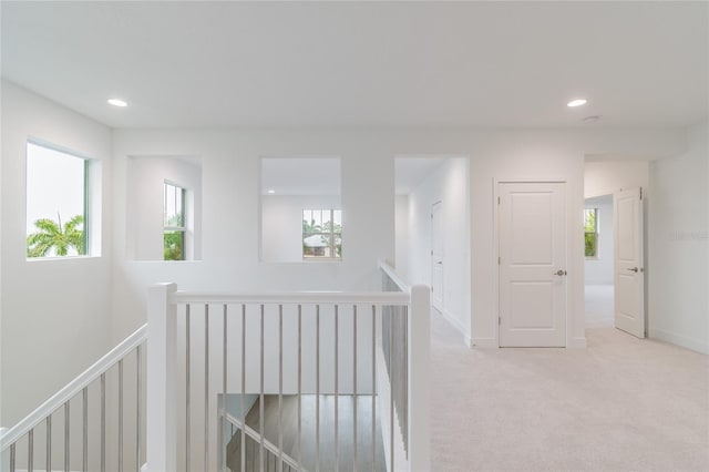 hallway with light colored carpet and a healthy amount of sunlight