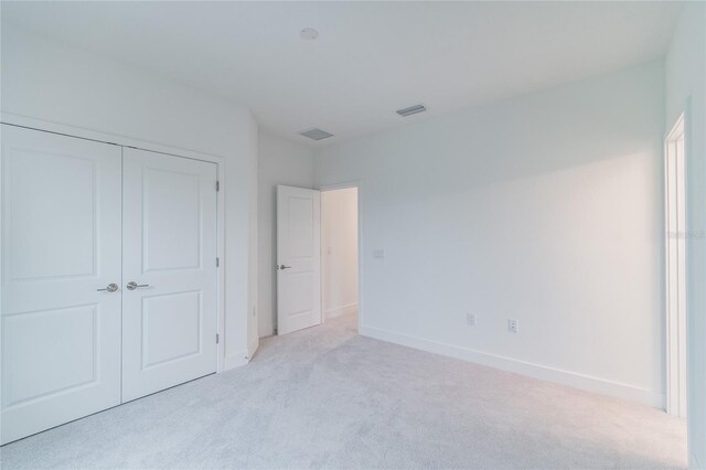 unfurnished bedroom with light colored carpet and a closet