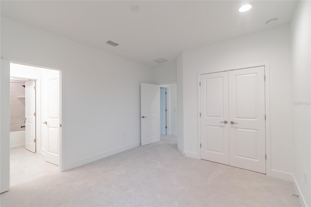 unfurnished bedroom with a closet and light colored carpet