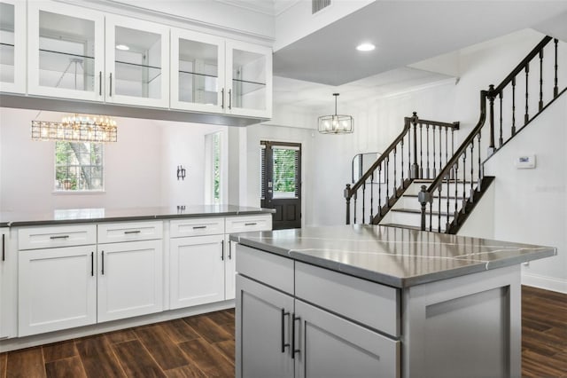 kitchen with decorative light fixtures, a center island, dark hardwood / wood-style flooring, a notable chandelier, and white cabinets