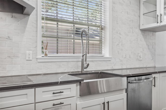 kitchen with sink, white cabinetry, dark stone countertops, dishwasher, and decorative backsplash