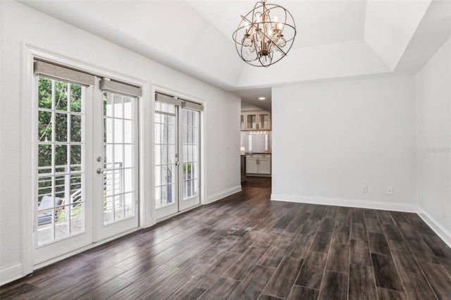 interior space featuring dark wood-type flooring, a chandelier, a raised ceiling, and french doors