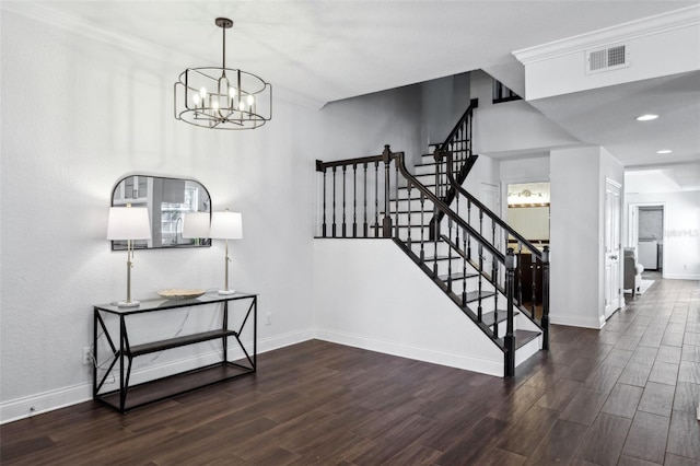 staircase featuring hardwood / wood-style flooring, crown molding, and an inviting chandelier