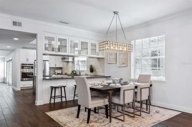 dining room with crown molding, sink, and dark hardwood / wood-style flooring