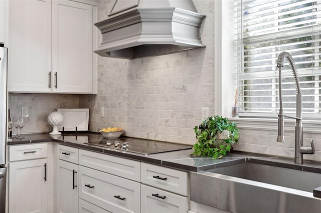 kitchen with custom range hood, sink, white cabinets, and black electric cooktop