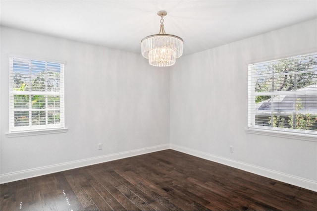 unfurnished room featuring a chandelier, dark hardwood / wood-style floors, and a healthy amount of sunlight