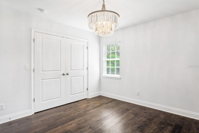 unfurnished bedroom with dark hardwood / wood-style flooring and a notable chandelier