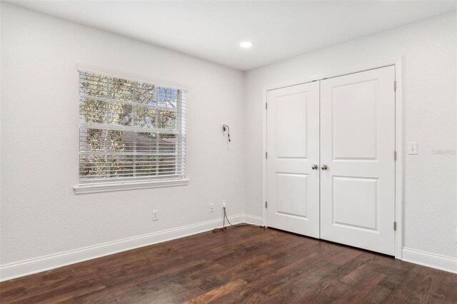 unfurnished bedroom with dark hardwood / wood-style flooring and a closet