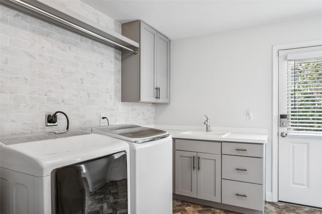 clothes washing area with separate washer and dryer, sink, and cabinets