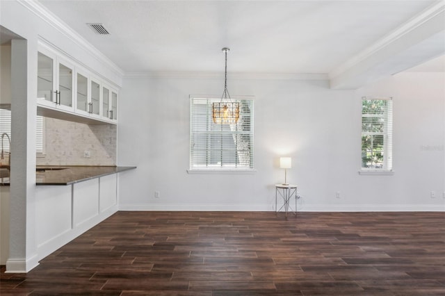 unfurnished dining area featuring dark hardwood / wood-style flooring, a notable chandelier, and ornamental molding