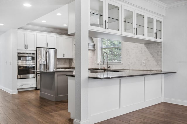 kitchen with white cabinetry, ornamental molding, kitchen peninsula, and appliances with stainless steel finishes