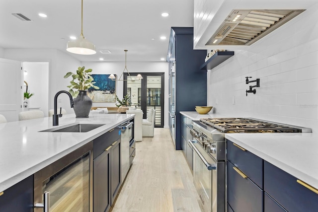 kitchen featuring pendant lighting, sink, high end stainless steel range oven, wine cooler, and light wood-type flooring