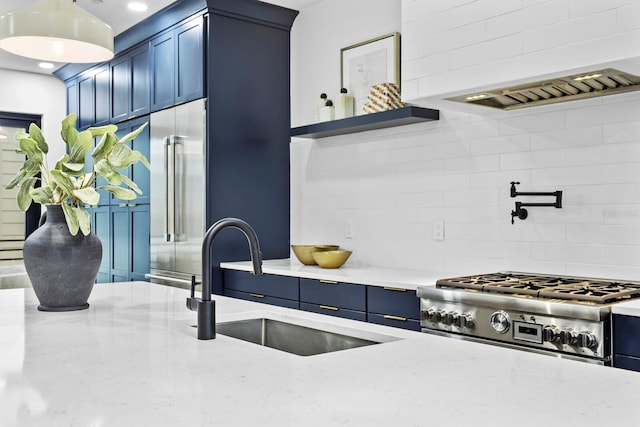 kitchen featuring high end appliances, backsplash, blue cabinets, sink, and light stone counters