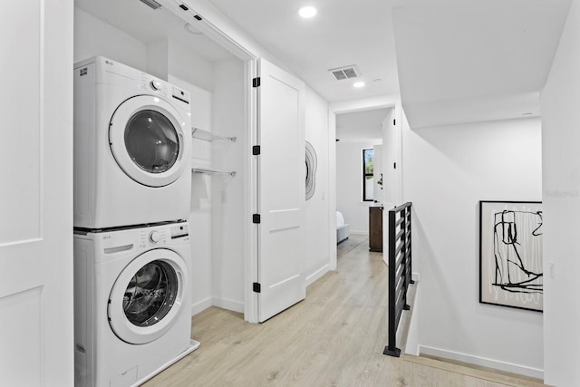 washroom with light hardwood / wood-style flooring and stacked washer and clothes dryer