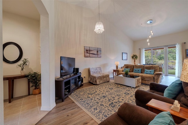 living room featuring an inviting chandelier, light hardwood / wood-style flooring, and lofted ceiling