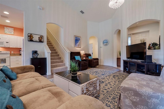 living room featuring a chandelier, a towering ceiling, and light hardwood / wood-style flooring