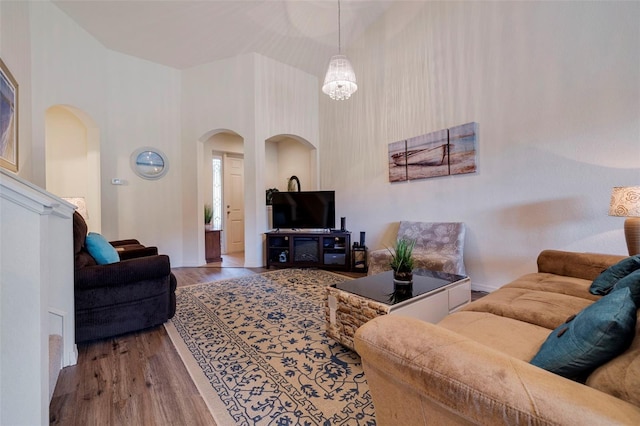 living room featuring wood-type flooring, high vaulted ceiling, and a notable chandelier