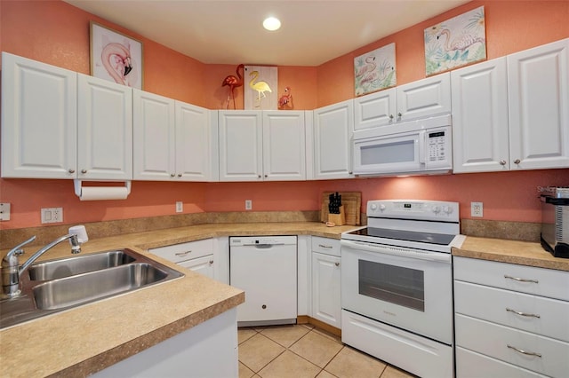 kitchen with white cabinetry, sink, light tile patterned flooring, and white appliances