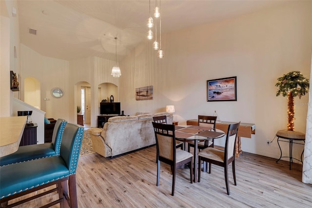 dining space with light hardwood / wood-style floors and high vaulted ceiling