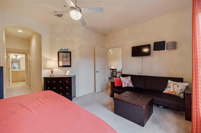 bedroom with light colored carpet, ceiling fan, and ensuite bathroom