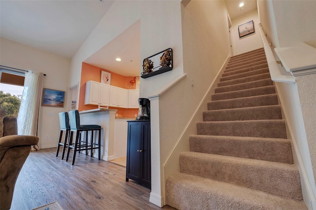 staircase with hardwood / wood-style flooring and lofted ceiling