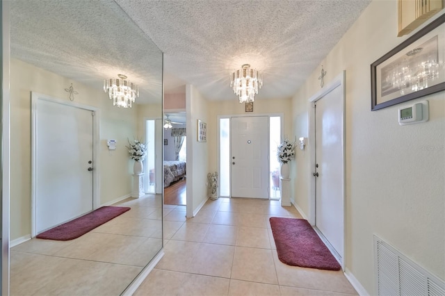 entrance foyer featuring a chandelier, light tile patterned floors, and a textured ceiling