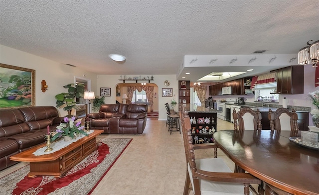 living room with sink, light tile patterned flooring, and a textured ceiling