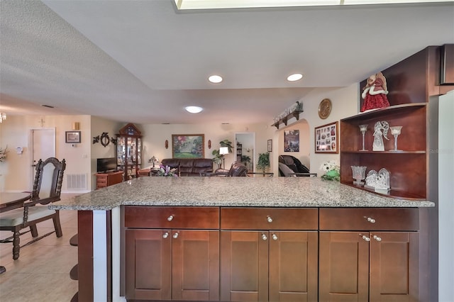 kitchen featuring kitchen peninsula, light stone countertops, light tile patterned flooring, and a textured ceiling