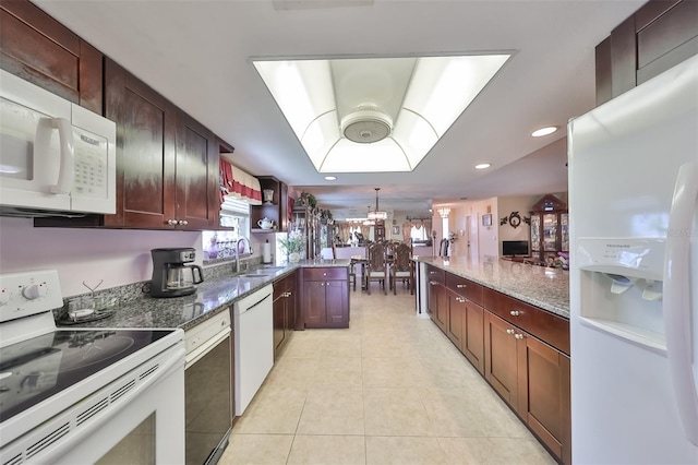 kitchen featuring white appliances, light tile patterned floors, pendant lighting, an inviting chandelier, and dark stone countertops