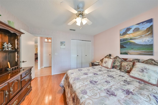 bedroom featuring ceiling fan, light wood-type flooring, a textured ceiling, and a closet